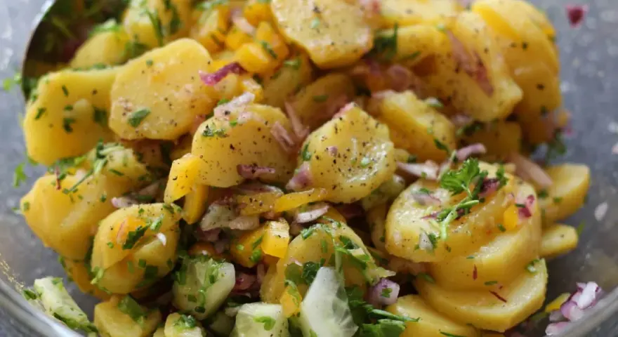 Omas sonntagsessen: Kartoffelsalat mit Gurken, Zwiebeln und frischen Kräutern, perfekt gewürzt.