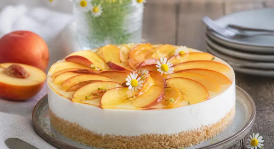 Eine **schnelle Torte** mit Pfirsichscheiben und Götterblümchen auf cremigem Käsekuchenboden.