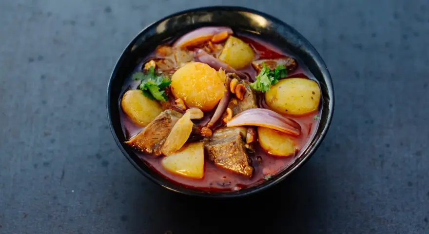Schüssel mit Massaman Curry, Kartoffeln, Fleisch, Zwiebeln und Koriander.