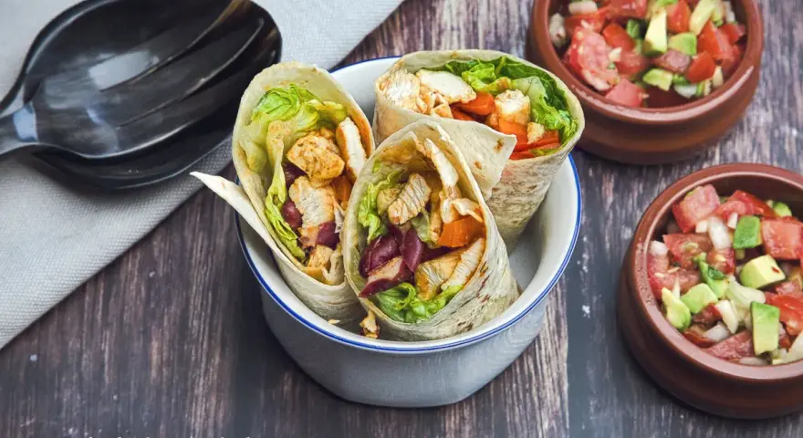 Drei leckere Wraps mit Hähnchen, Salat und Bohnen, perfekt zum Mexicana selber machen. Dazu frische Salsa in kleinen Schalen.