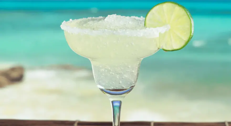 Erfrischende Margarita mit Salzrand und Limettenscheibe, perfekt für ein Strand-Margarita-Rezept.