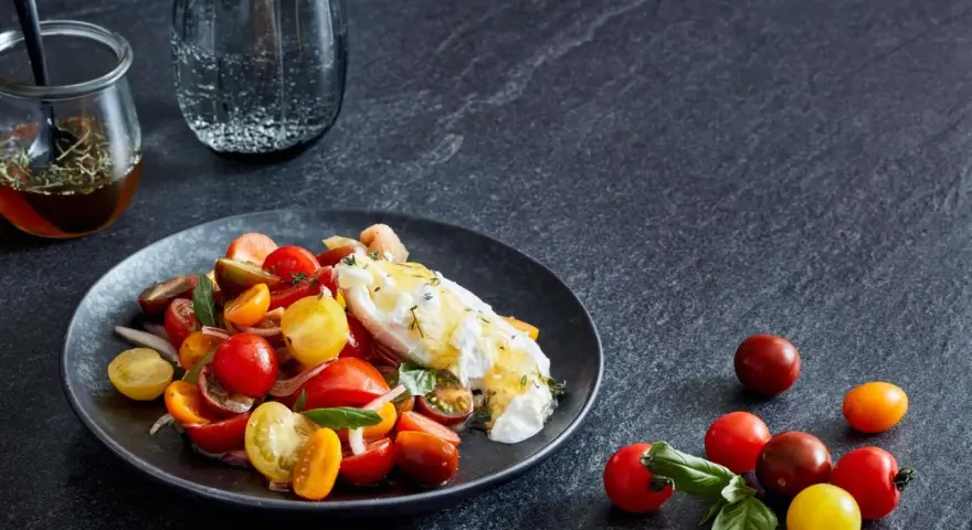 Bunter Tomatensalat mit cremiger Burrata, garniert mit frischen Kräutern. Ein köstlicher Genuss!