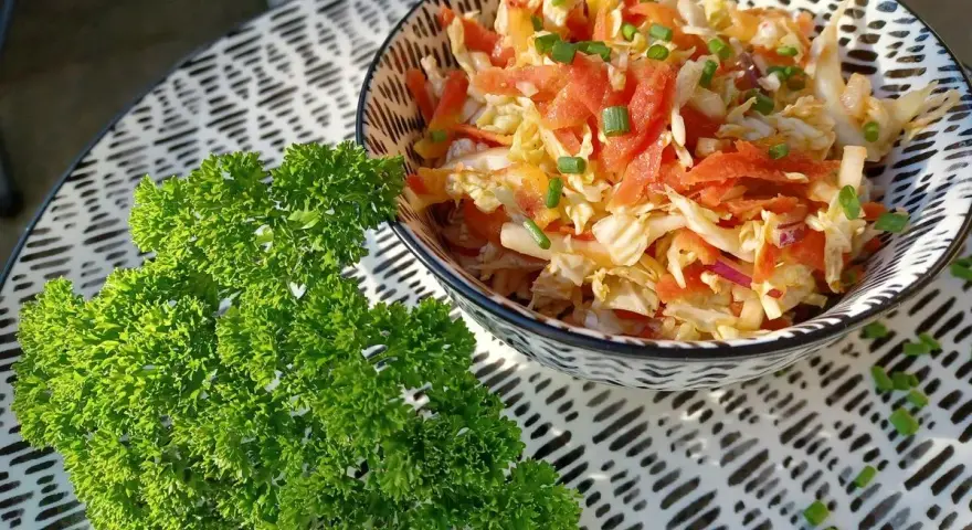 Frischer Chinakohlsalat mit Honig-Senf Dressing, garniert mit Lachs und Schnittlauch. Daneben ein Bund glatte Petersilie.