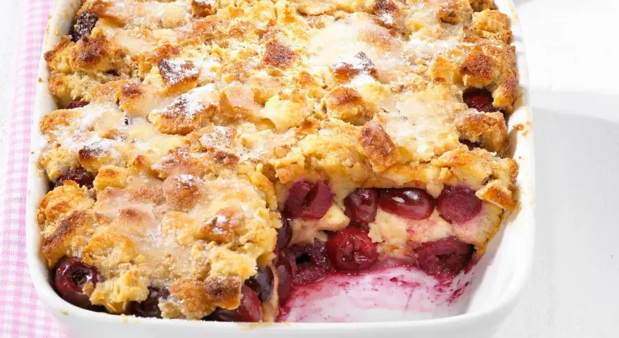 Omas Kirschenmichel Rezept: Ein goldbrauner Auflauf mit saftigen Kirschen und knuspriger Streuselhaube, bestäubt mit Puderzucker.