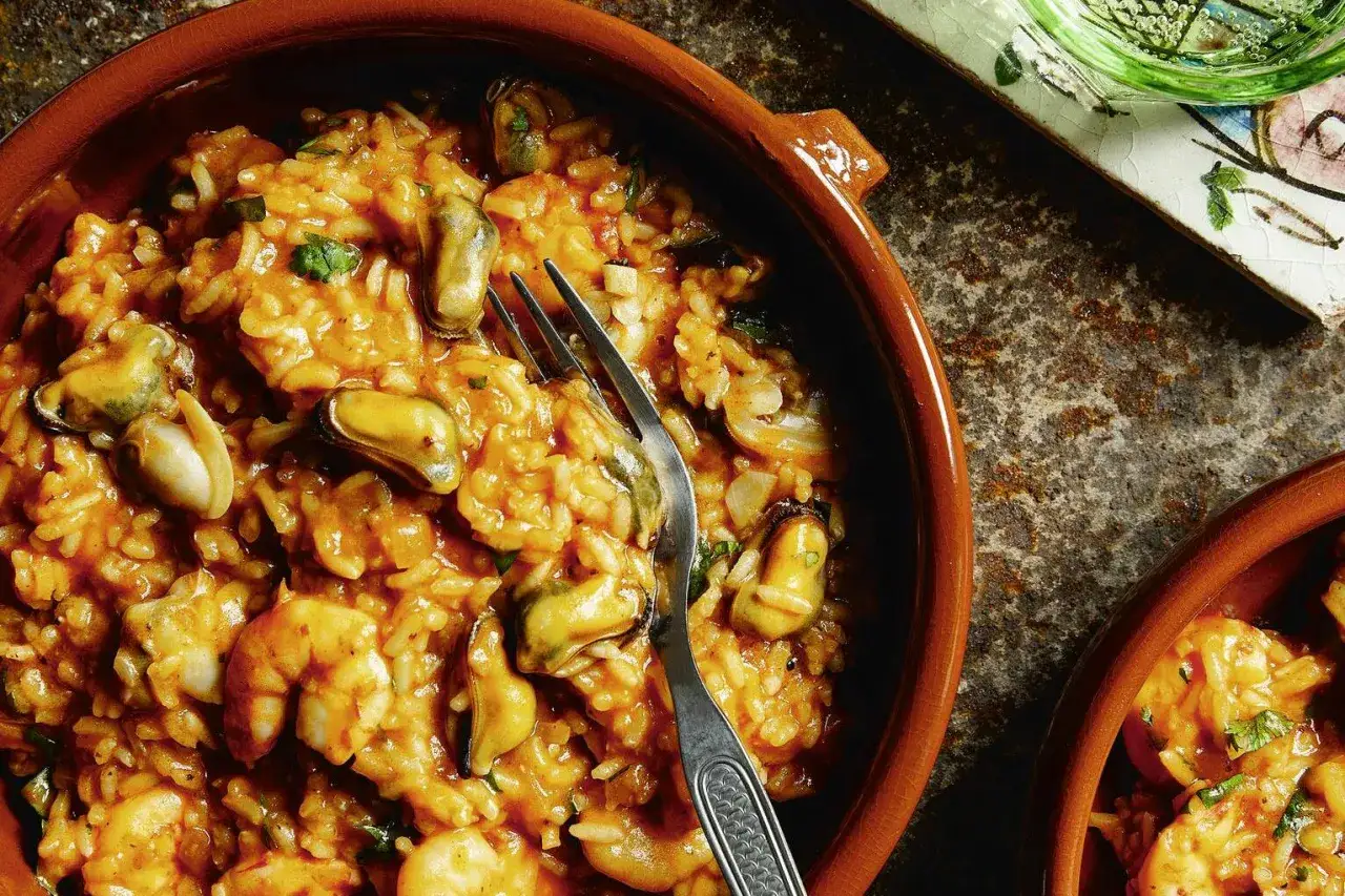 Ein k&ouml;stliches Arroz de Marisco mit Garnelen und Muscheln in einer Tonschale, bereit zum Genie&szlig;en.