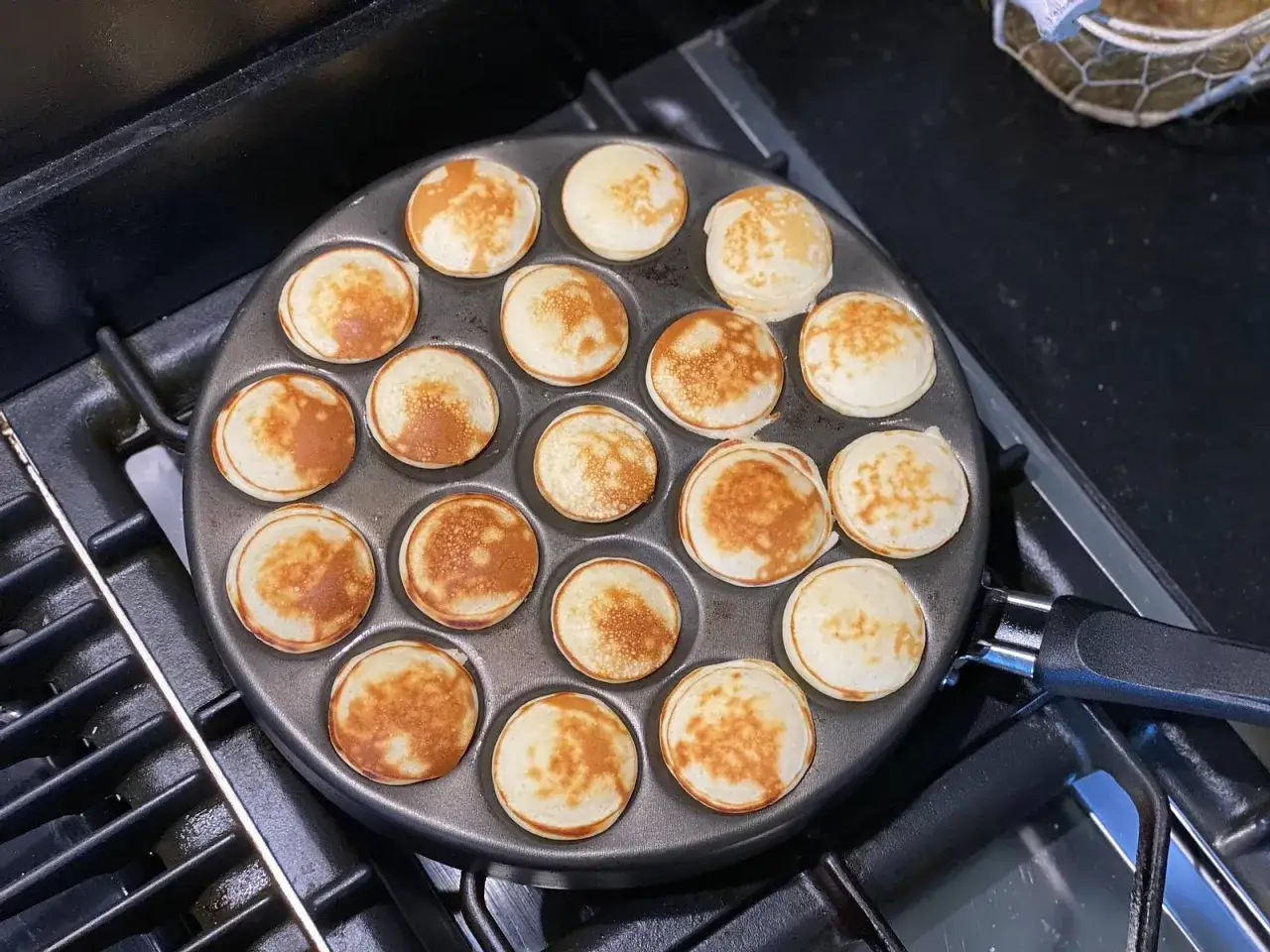 Kleine, goldbraune Poffertjes werden in einer Pfanne gebacken. Ein k&ouml;stliches Rezept f&uuml;r s&uuml;&szlig;e Leckereien.