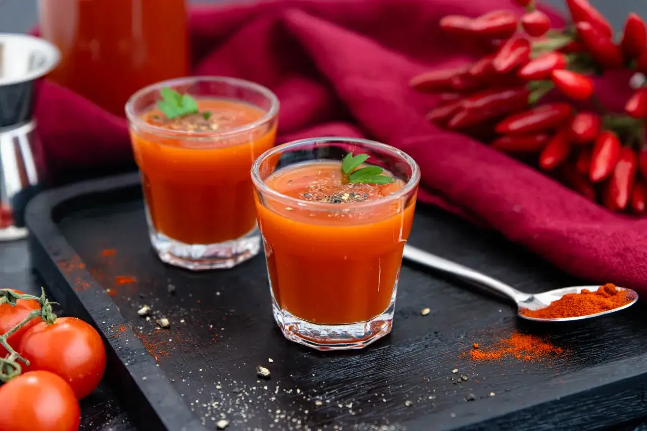 Zwei Gl&auml;ser w&uuml;rziger Tomatensaft, perfekt f&uuml;r ein mexikaner rezept. Frische Tomaten und Chilis im Hintergrund.