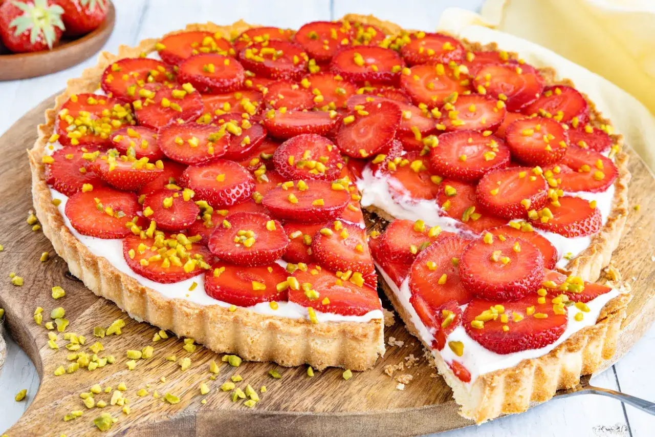 Ein köstlicher Erdbeerkuchen mit Quark, belegt mit frischen Erdbeerscheiben und gehackten Pistazien. Ein perfektes Erdbeerkuchen Rezept für den Sommer.