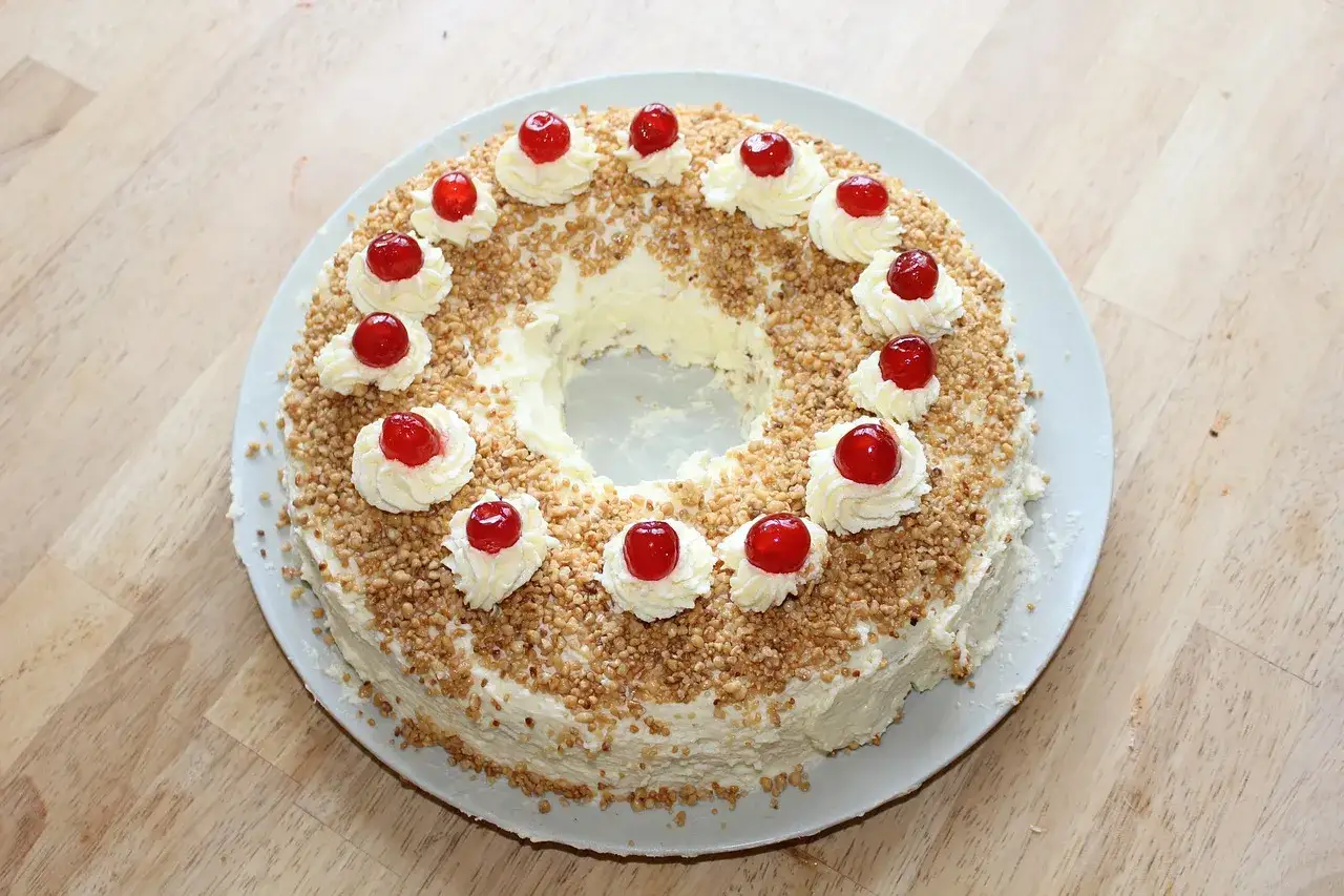 Ein Kranzkuchen mit Buttercreme, gehackten N&uuml;ssen und Kirschen. Perfekt f&uuml;r beste Torten Rezepte!