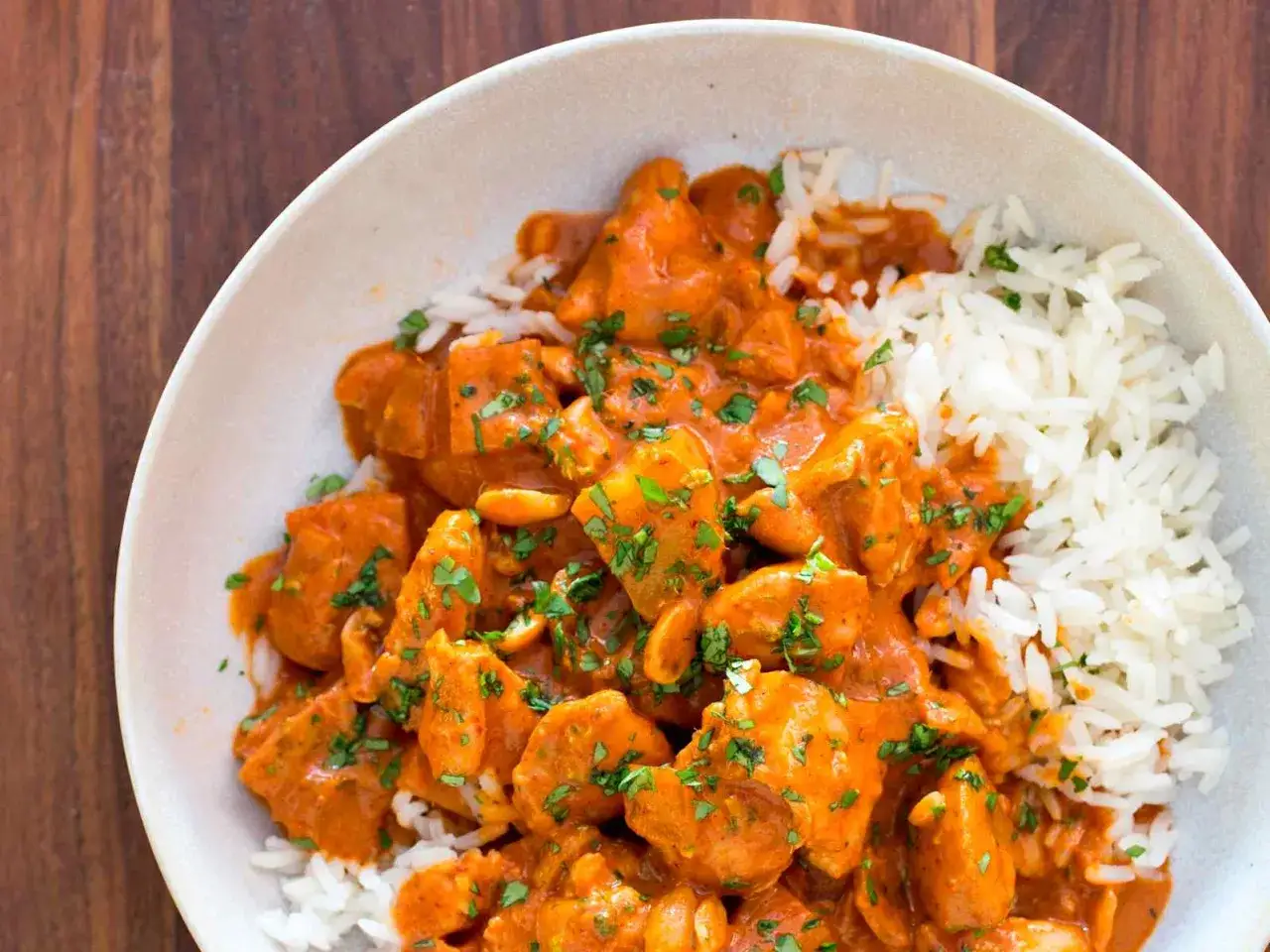 Ein Teller mit cremigem Massaman Curry mit H&uuml;hnchen und Reis, garniert mit frischer Petersilie.