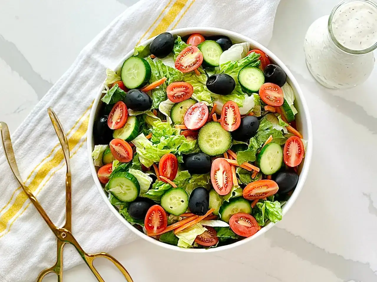 Frischer Salat mit Gurken, Tomaten und schwarzen Oliven &ndash; ein Beispiel f&uuml;r ausgefallene Salate, serviert mit Dressing.