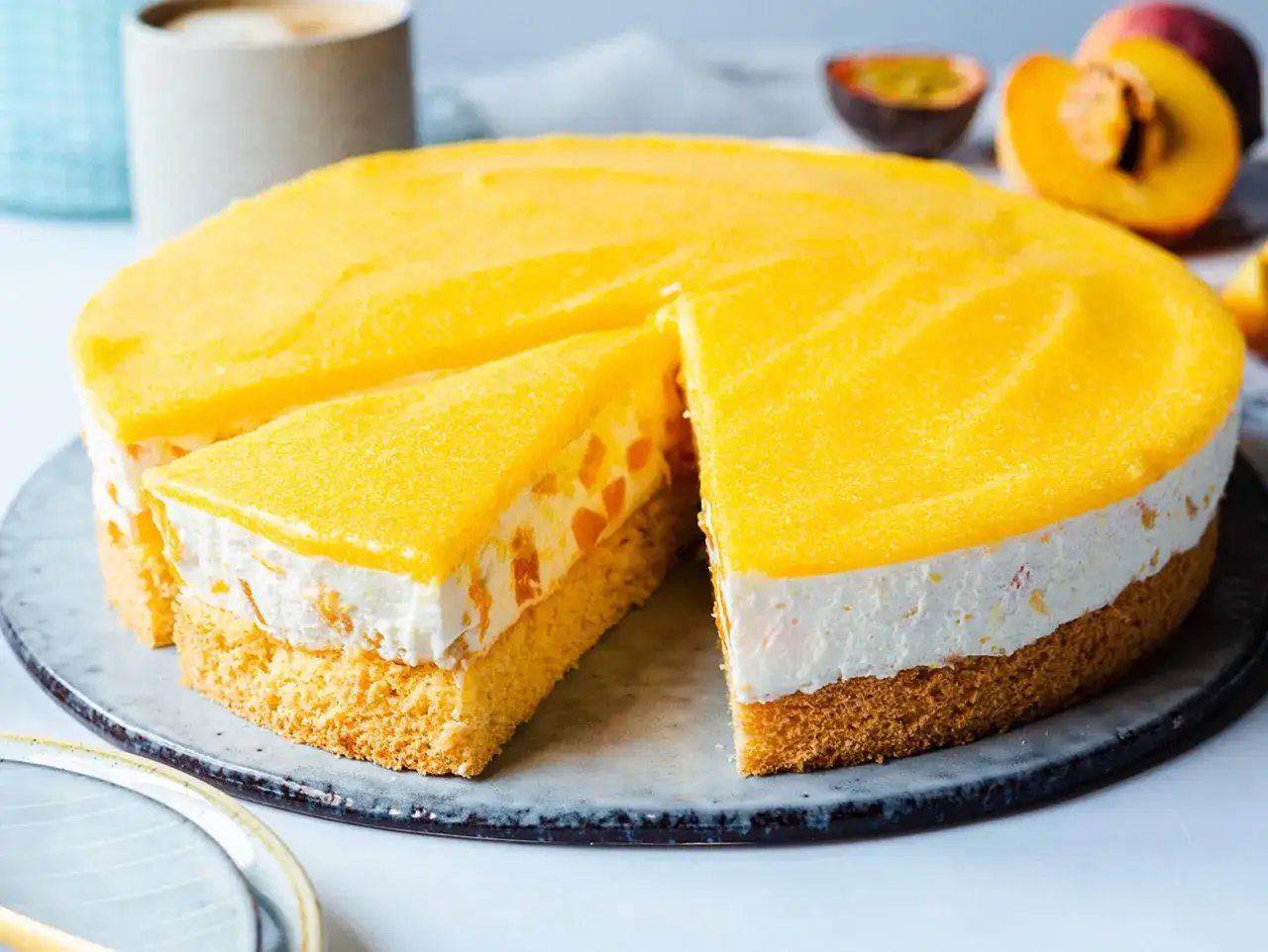 Eine saftige Pfirsich Maracuja Torte mit Biskuitboden, cremiger F&uuml;llung und fruchtigem Topping. Ein St&uuml;ck ist bereits angeschnitten.