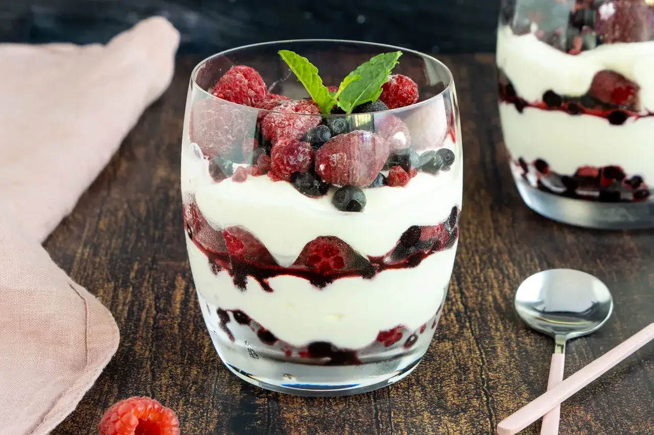 Cremiges Mascarpone-Dessert mit frischen Beeren und Minze in einem Glas geschichtet.