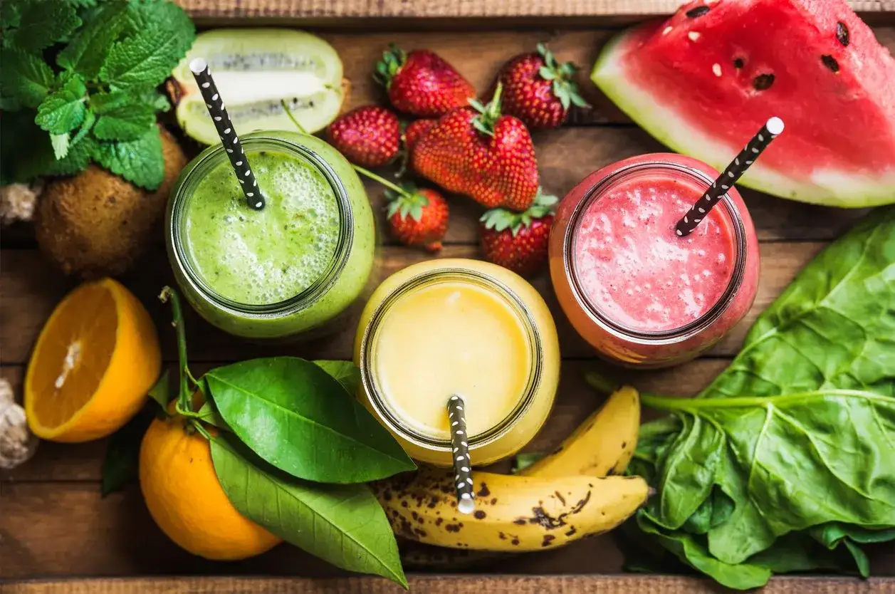 Drei bunte Smoothies mit Fr&uuml;chten wie Erdbeeren, Kiwi, Banane und Wassermelone. Perfekt f&uuml;r gesunde smoothie rezepte.