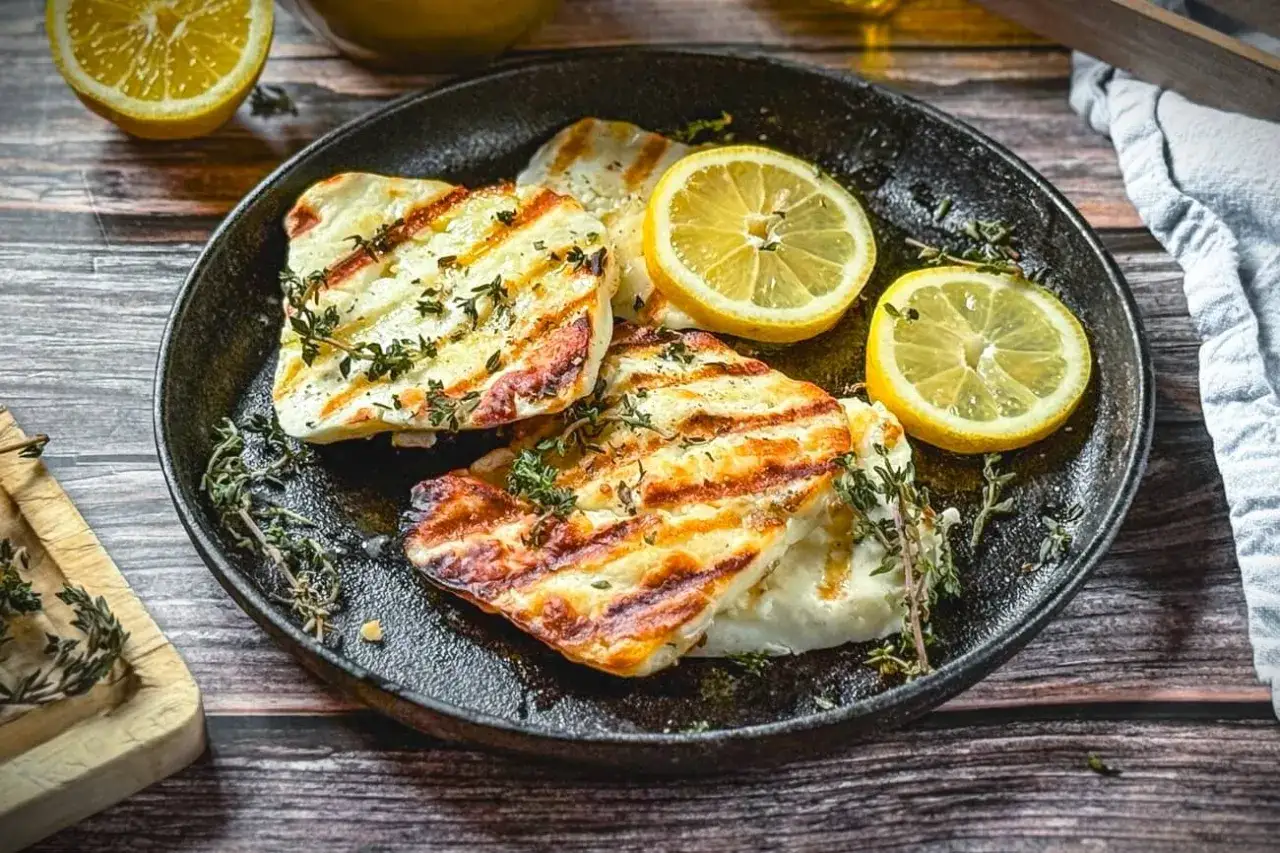 Perfekt gegrillter Halloumi mit Kr&auml;utern und Zitronenspalten auf einer Gusseisenplatte. Ein Genuss f&uuml;r alle Sinne!