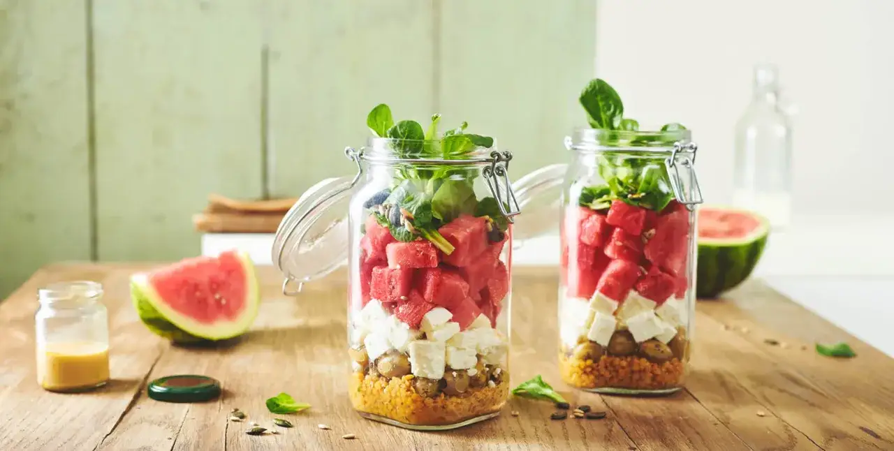 Zwei Gl&auml;ser mit einem bunten Salat: Wassermelone, Feta, Kichererbsen und gr&uuml;nes Blattgem&uuml;se sind geschichtet.