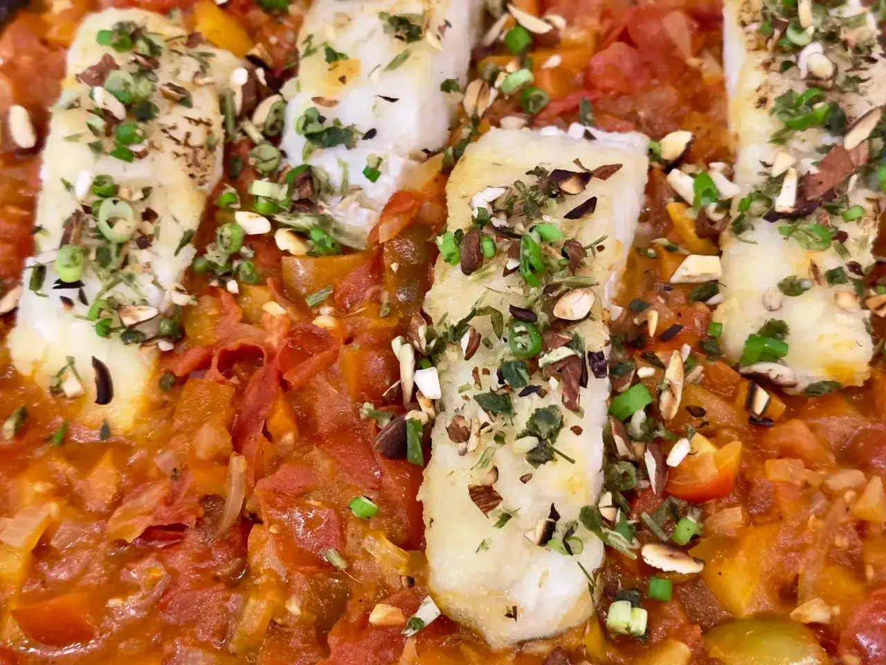 Fischfilets in Tomatensoße mit Mandeln und Frühlingszwiebeln. Ein köstliches Gericht, das sich perfekt für Fischrezepte eignet.