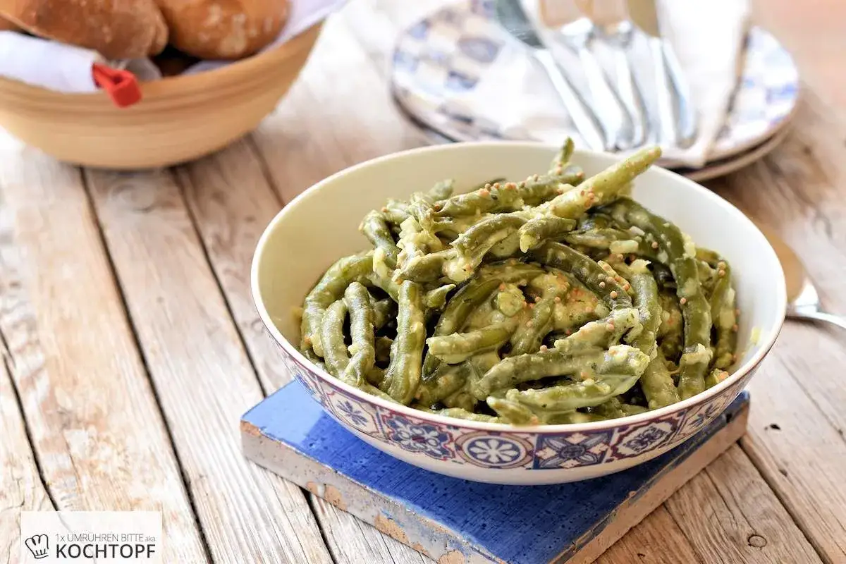 Gr&uuml;ner Bohnensalat mit cremigem Dressing, garniert mit Senfk&ouml;rnern. Ein k&ouml;stlicher Bohnensalat, der mit seinem Dressing begeistert.