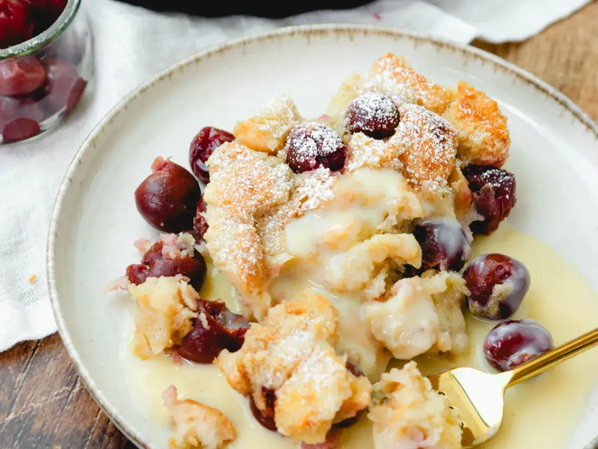 Omas Kirschenmichel Rezept: Ein warmer, s&uuml;&szlig;er Auflauf mit Kirschen und Vanillesauce, best&auml;ubt mit Puderzucker.