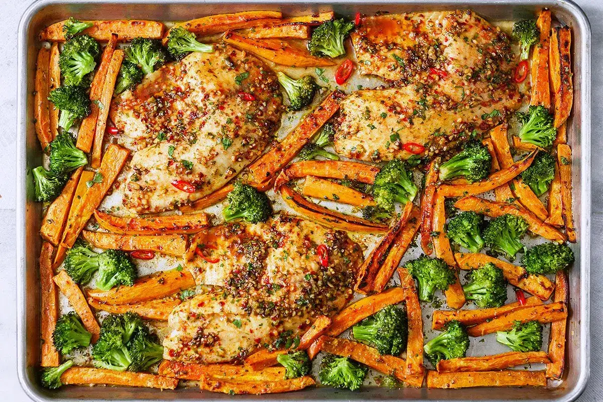 Ein k&ouml;stliches Fischpfanne Rezept: Gebratenes Fischfilet mit S&uuml;&szlig;kartoffel-Pommes und Brokkoli auf einem Backblech.
