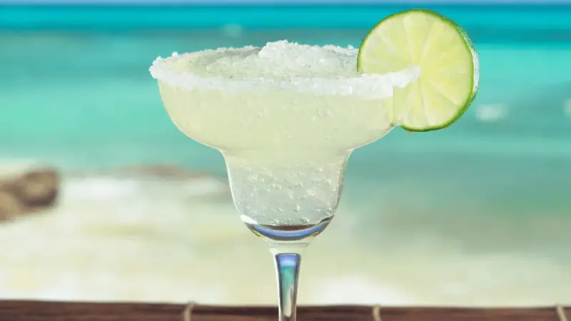 Erfrischende Margarita mit Salzrand und Limettenscheibe, perfekt für ein Strand-Margarita-Rezept.